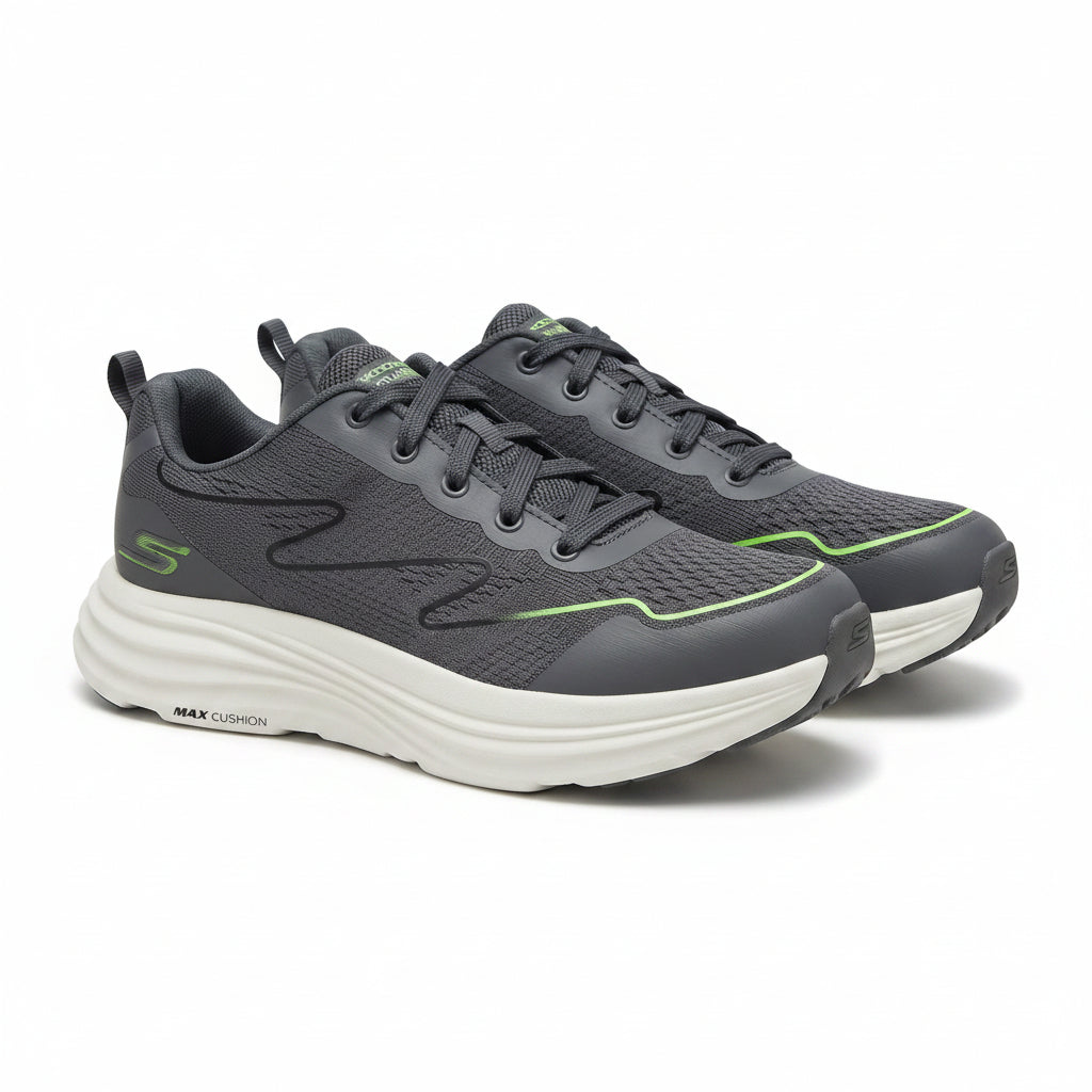 A pair of Skechers Max Cushion athletic sneakers in dark gray and black with bright green accents and a thick white sole, shown against a solid beige background.