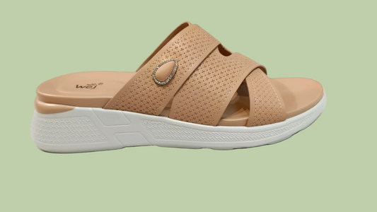 Tan sandal with white sole on a tiled floor