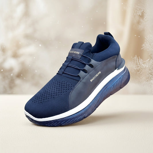A Skechers athletic sneaker in navy blue and dark gray with a white midsole, shown from a three-quarters angle on a white background.