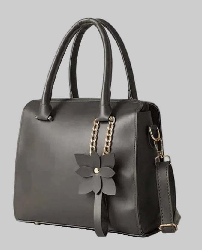 Black handbag with a floral accessory on a white background