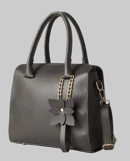 Black handbag with a floral accessory on a white background