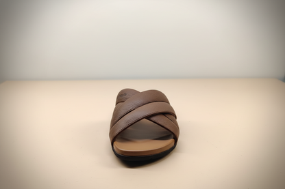 Brown sandal with criss-cross straps on a light background