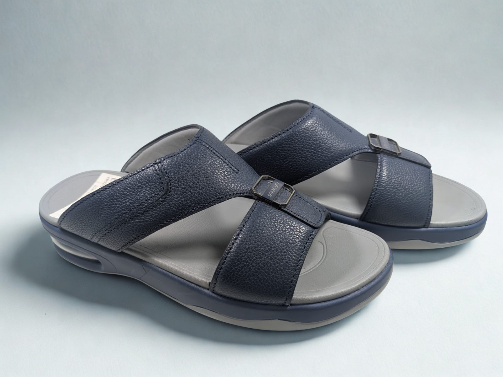 Pair of navy sandals with gray soles on a light gray background