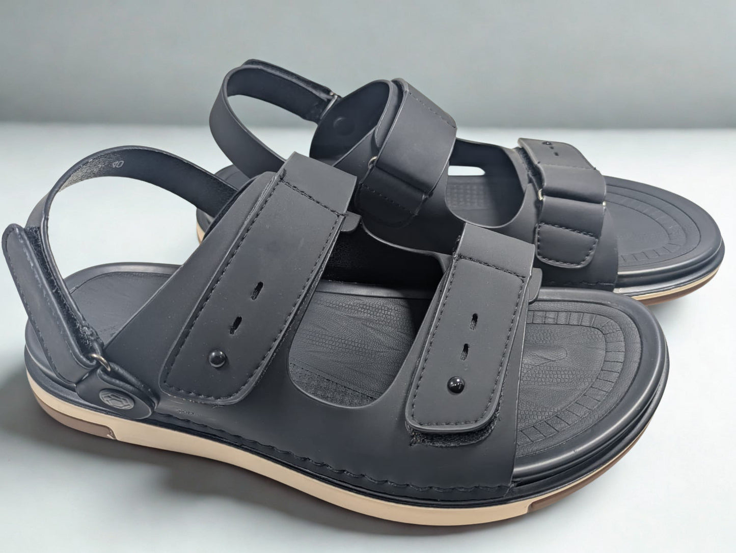 Pair of gray sandals with multiple straps on a light gray background