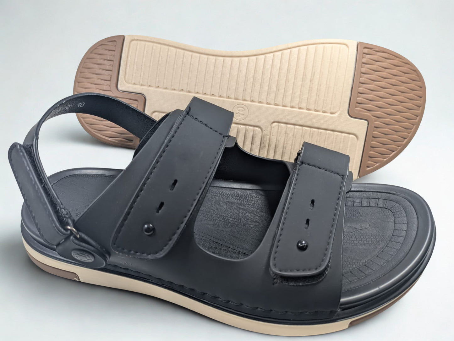 Black sandal with beige sole on a light gray background