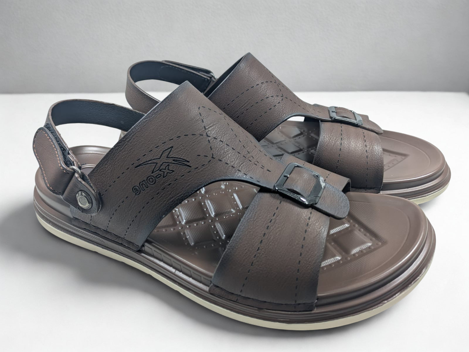 Pair of brown sandals with buckles on a white surface