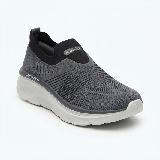 A dark gray and black slip-on sneaker with a thick white sole, shown from a three-quarters angle on a white background.