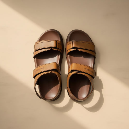 Pair of brown sandals with multiple straps on a light gray background