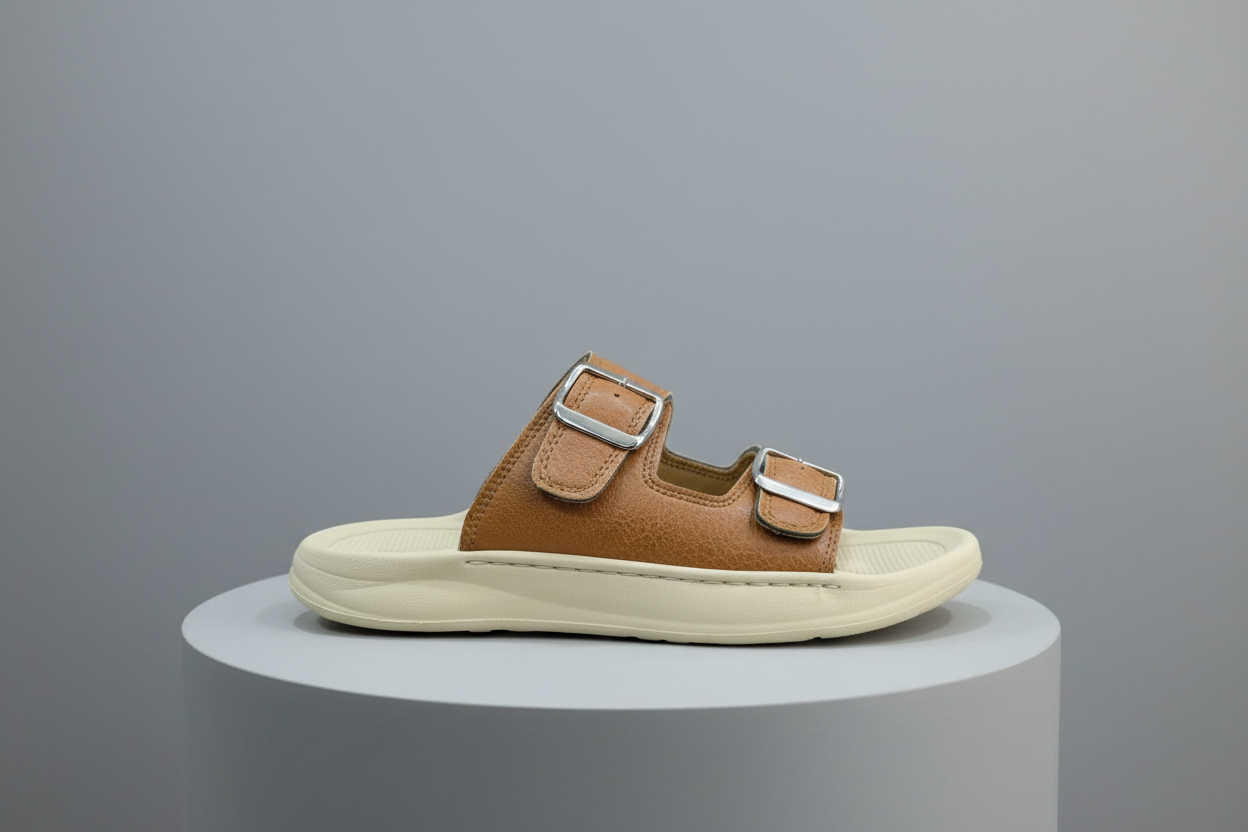 Brown sandal with silver buckles on a gray surface