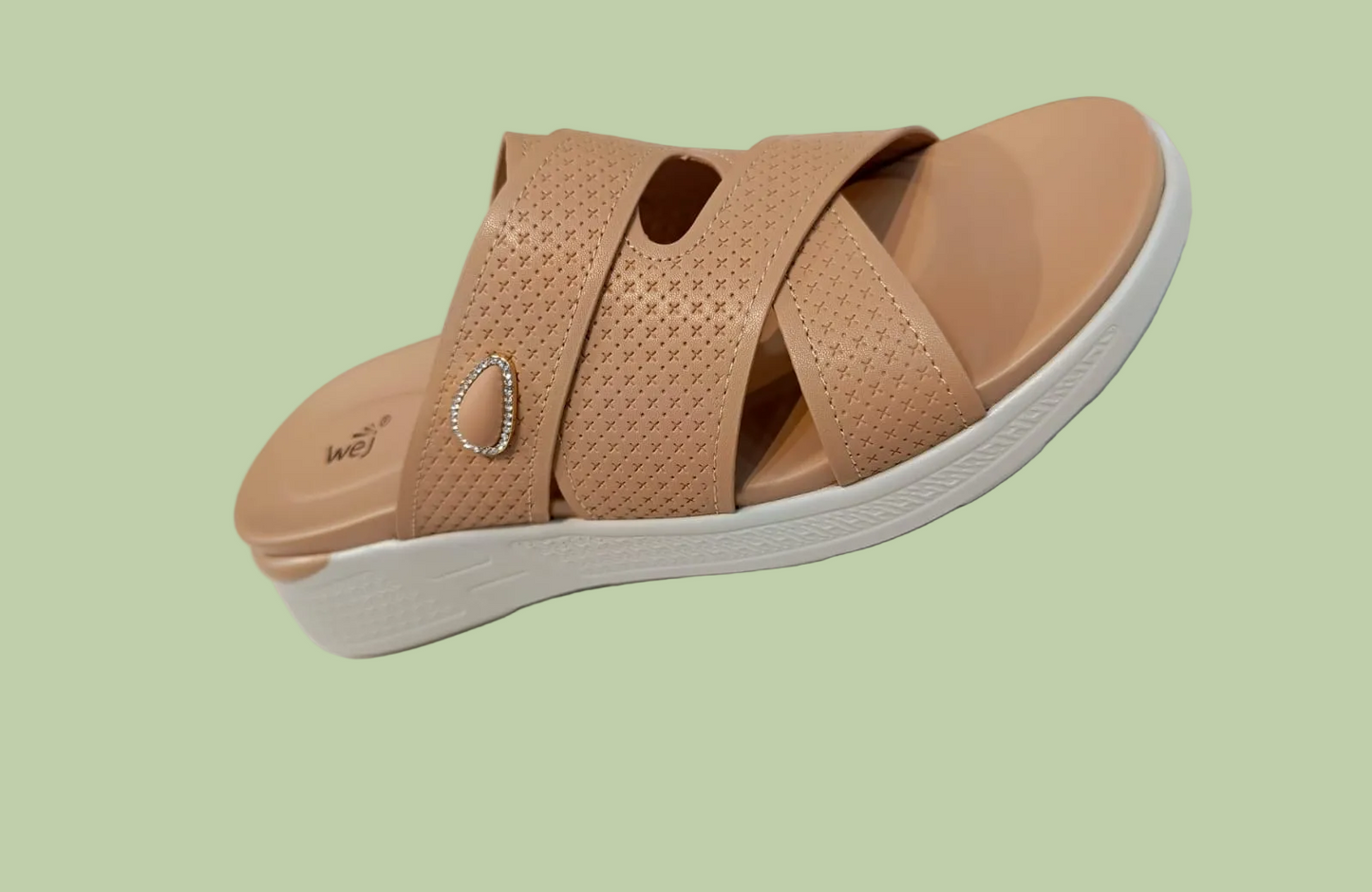 Tan sandal with a heart-shaped embellishment on a white surface