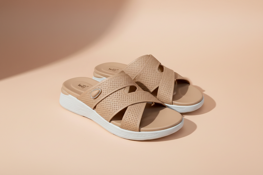 Tan sandals with a brand logo on a light tiled floor