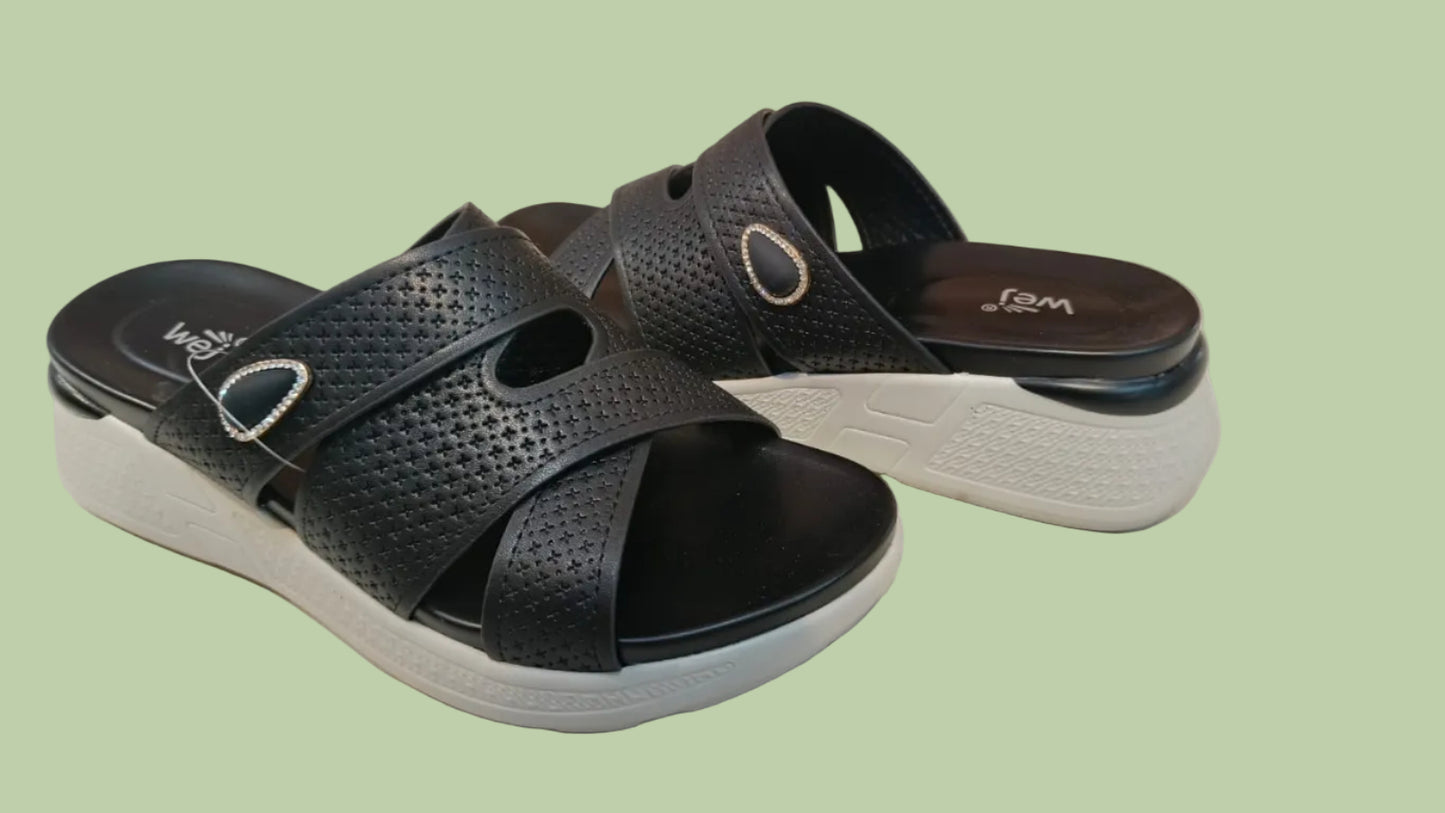 Black sandals with white soles on a tiled floor