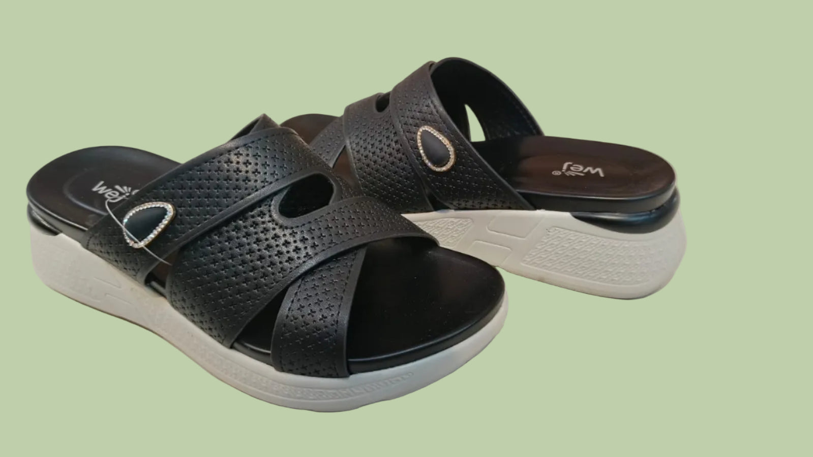 Black sandals with white soles on a tiled floor