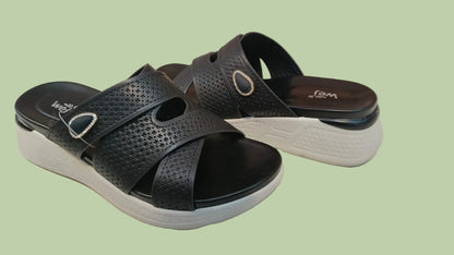 Black sandals with white soles on a tiled floor