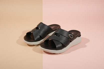 Black sandals with white soles on a tiled floor