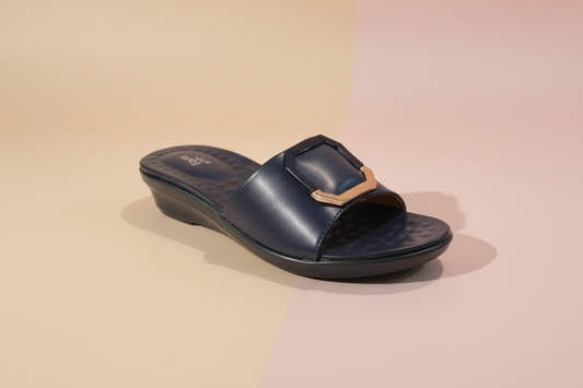 Black sandal with a gold buckle on a light-colored floor.
