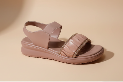 Pink sandal with gold accents on a light-colored floor